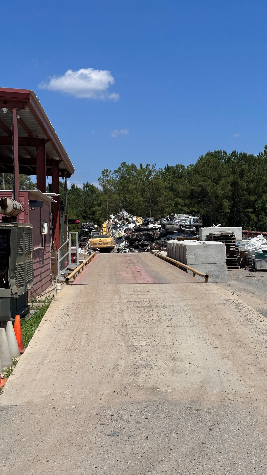 Wide view of the Veterans Metal Recycling yard at Gulfport with the scale ramp and sorted material piles in warm afternoon light