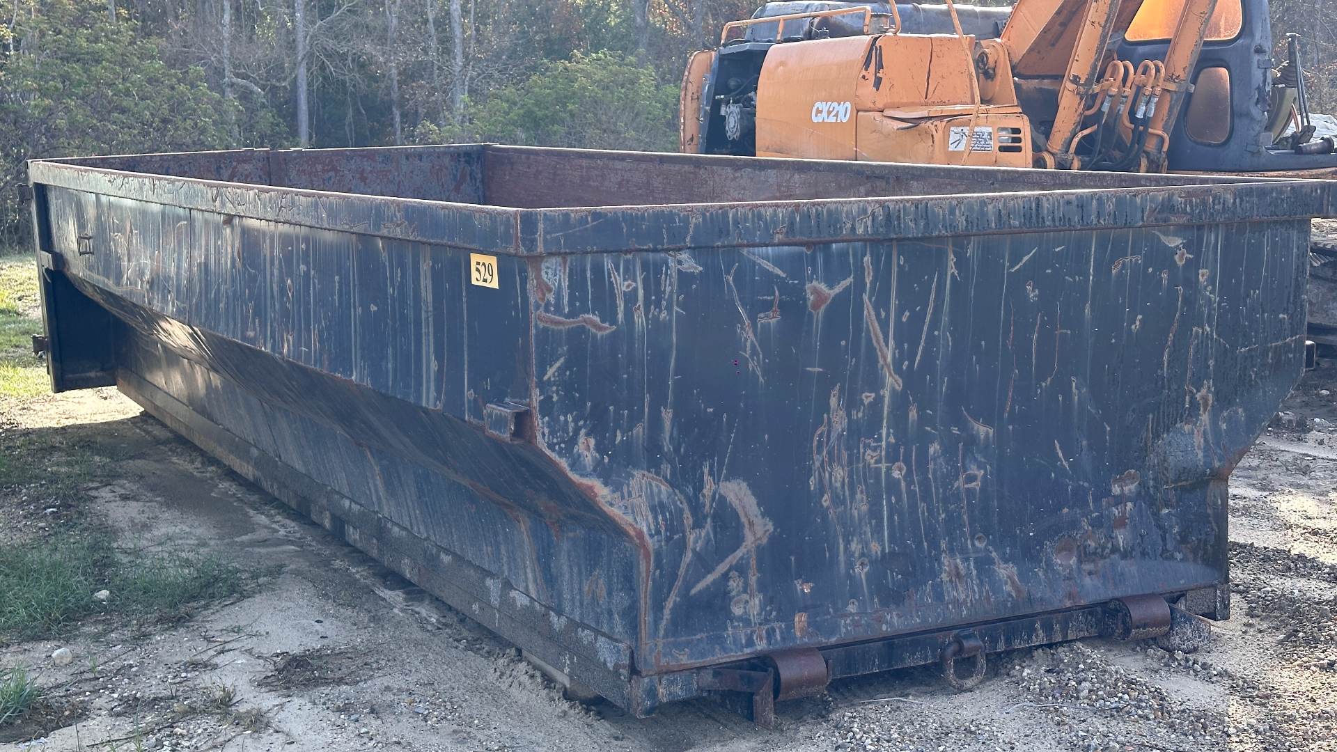 20-yard open-top roll-off container #529 spotted at a facility with a Case CX210 excavator standing by for a scrap load-out